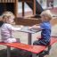 Enfants assis à un banc et une table carrés dans une aire de jeux