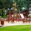 Structure de terrain de jeu en bois Mastodont castle with slide dans un parc
