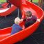 Des enfants jouent sur le toboggan rouge du château Mastodon avec toboggan.