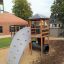Structure de jeu en bois Six Angle Aztec avec mur d’escalade et toboggan dans une cour d’école.