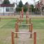 Équipement de terrain de jeu extérieur Single Somersault Nature avec poteaux en bois et barres métalliques.