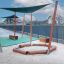 Sun Shade Triangle 3x3x3 Pioneer (Larchwood) installé au-dessus du bac à sable de l’aire de jeux avec des poteaux en bois