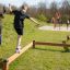 Des enfants jouent sur les poutres d'équilibre Classic Nature Trim Trail dans un parc.
