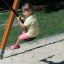 Enfant se balançant sur une balançoire en corde dans une aire de jeux.