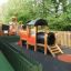Locomotive with slide train playhouse dans une aire de jeux clôturée.