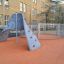 Aztec arch steel structure sur une surface de jeu orange dans un cadre scolaire urbain.