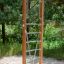 Vertical wooden ladder dans une aire de jeux entourée d’arbres.