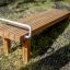 Gymnastic bench en lattes de bois avec une poignée en métal dans un environnement extérieur.