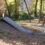 Hill Slide h150 dans une aire de jeux entourée d’arbres en automne.
