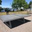 Concrete table tennis, free-standing sur une terrasse extérieure près de l'eau.