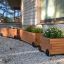 Trois jardinières Wooden flowerpot II avec des fleurs, à l’extérieur d’une maison.