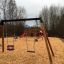 Swing Frame (double swing) sur une aire de jeux avec des copeaux de bois et un toboggan en arrière-plan