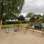 Swing Frame (double swing) dans une aire de jeux avec un toboggan et des structures d'escalade.