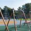 Swing Frame (double swing) dans une aire de jeux colorée avec d'autres structures de jeu en arrière-plan