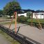 Swing Frame (double swing) dans une aire de jeux avec poutres de soutien en bois et surface en sable.