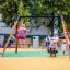 Enfant se balançant sur Swing Frame (single swing, wide) dans une aire de jeux avec des spectateurs.