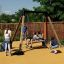 Des enfants jouent sur un Swing Frame (single swing, wide) dans une aire de jeux.