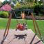 Trois enfants jouent sur un Swing Frame (single swing, wide) dans un parc.