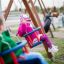 Des enfants jouent sur un siège de balançoire : siège bébé dans une aire de jeux.