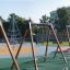 Swing seat: Safety seat sur une aire de jeux avec une structure d'escalade et d'autres équipements de jeu à l'arrière-plan