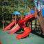 Slide rouge sur une aire de jeux avec des arbres en arrière-plan
