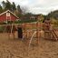 Panther wooden playhouse dans une aire de jeux sablonneuse avec des structures d’escalade et des toboggans.