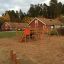 Panther wooden playhouse dans une aire de jeux avec toboggans et structures d’escalade.