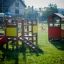 Ensemble de terrain de jeu en bois Mini play avec toboggans et maisonnette sur l’herbe.