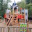 Terrain de jeu château Camelot en bois avec toboggan et éléments d’escalade pour enfants.