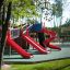 Slide rouge sur une aire de jeux avec plusieurs Slides et structures d'escalade