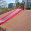 Slide rouge installé sur une colline d'aire de jeux.