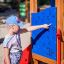 Jeune fille jouant avec un panneau éducatif sur une maisonnette intelligente avec toboggan.