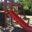 Zebra single slide dans une aire de jeux avec un toboggan rouge et des éléments d’escalade