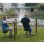 Deux personnes âgées utilisant l'équipement d'exercice Training twist & sit dans un parc près d'une fontaine.