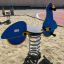 Équipement de jeu Scooter rocking avec design bleu et jaune dans une zone sablonneuse