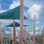 Sun Shade Triangle 3x3x3 Nature (Robinia) installé dans une aire de jeux avec des supports en bois.