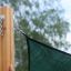 Sun Shade Triangle 5x5x5 Pioneer (Larchwood) fixé à un poteau en bois.