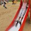 Enfant glissant sur le Single Swing with Tower single slide dans une aire de jeux.