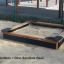 Bac à sable en bois avec Dino sandbox base dans une aire de jeux extérieure.