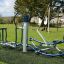 Équipement de fitness extérieur Set 8 installé sur une aire de jeux avec de l’herbe verte et un arbre en arrière-plan.