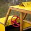 Aire de jeux en bois jaune Taxi avec volant rouge.