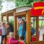 Des enfants jouent sur une voiture de pompiers en bois dans l’aire de jeux.