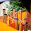 Équipement de jeu en bois Gamma pour enfants, avec toboggans colorés et structures d’escalade.