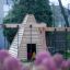 Wigwam wooden house dans un cadre d’aire de jeux avec des fleurs roses au premier plan