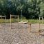 Équipement de jeux extérieur mettant en avant le Double Jump Bars sur un sol en copeaux de bois avec des arbres en arrière-plan.