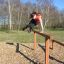Une femme saute par-dessus Double Jump Bars dans un parc.