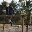 Athlète grimpant sur l'équipement de fitness extérieur Double Jump Bars.