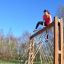Femme grimpant sur V-shape Net Large climbing net dans une aire de jeux extérieure.