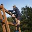 Un homme grimpe sur Step And Climb wooden ladder en extérieur.