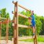 Un garçon grimpe sur Step And Climb wooden ladder dans une aire de jeux.